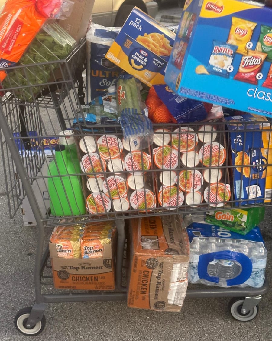 A shopping trolley loaded with noodles, bottled water, bread and other staples.